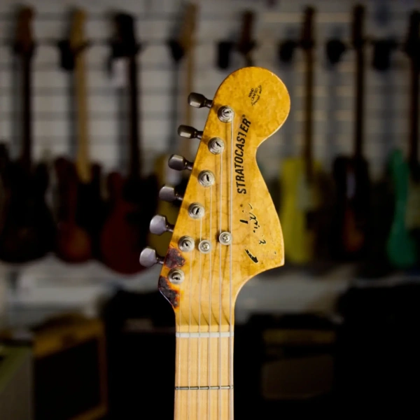 Close up of a vintage 1970s Greco Stratocaster guitar headstock with tuners and logo
